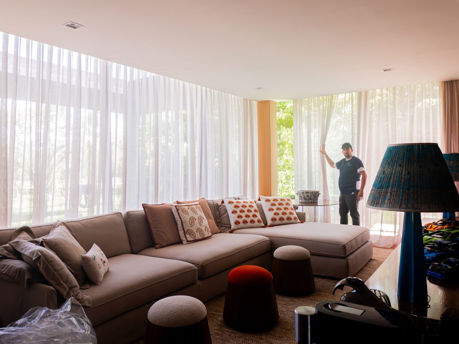 Profissional da Prime Cortinas ajustando a cortina de voil de uma sala ampla, depois da higienização